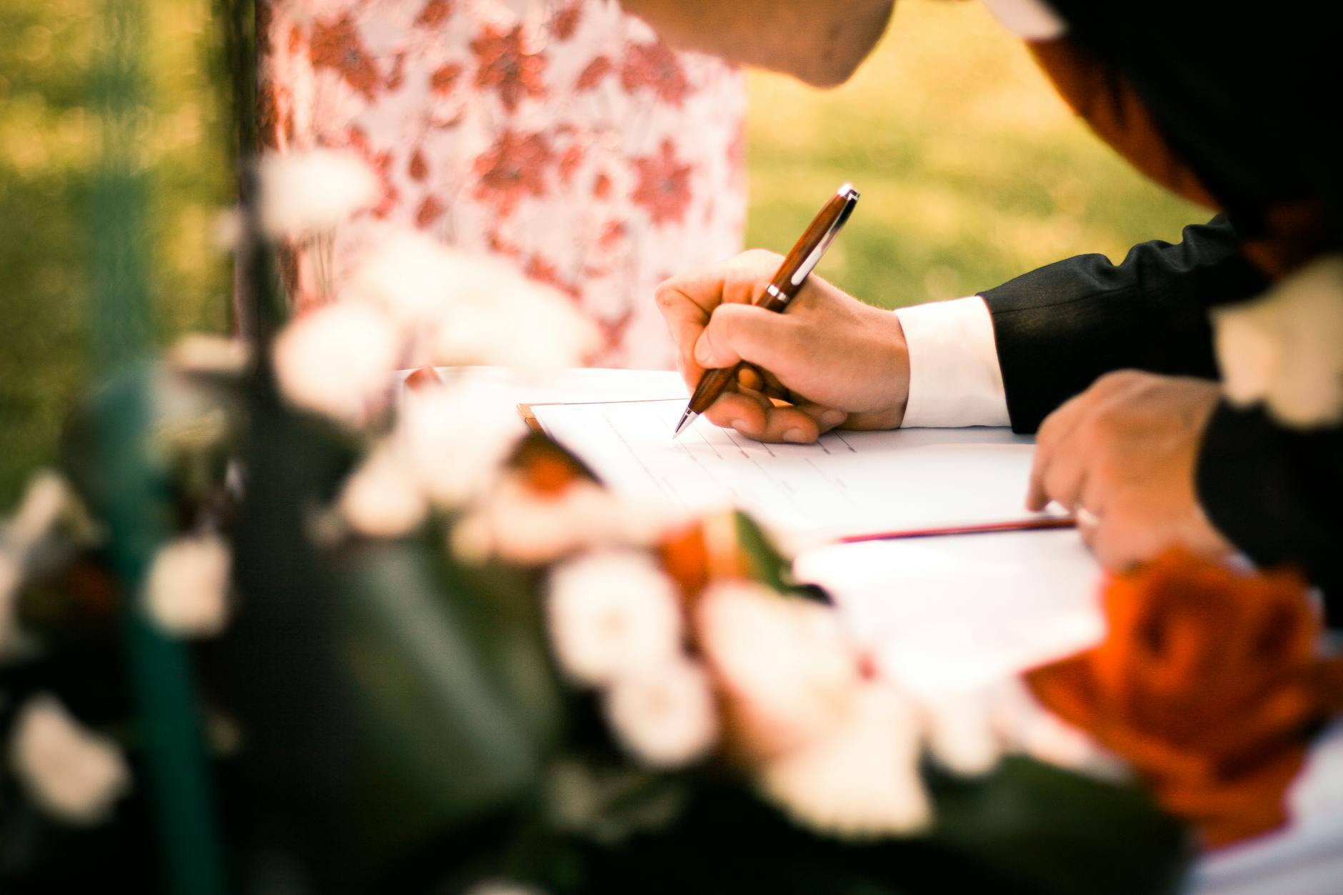 Para podpisuje dokumenty ślubne podczas plenerowej ceremonii