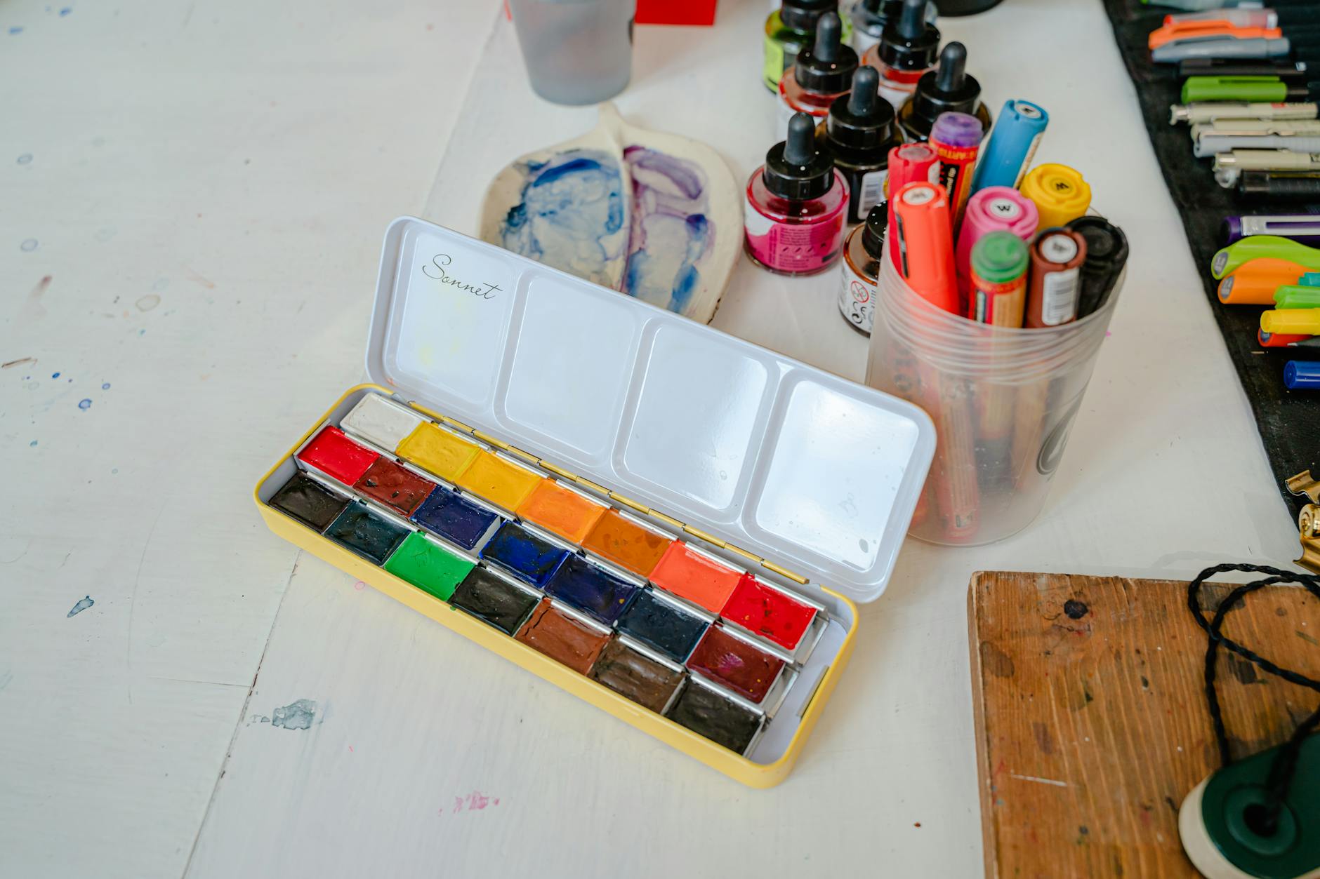 Kolorowe akwarele i markery rozłożone na kreatywnym biurku