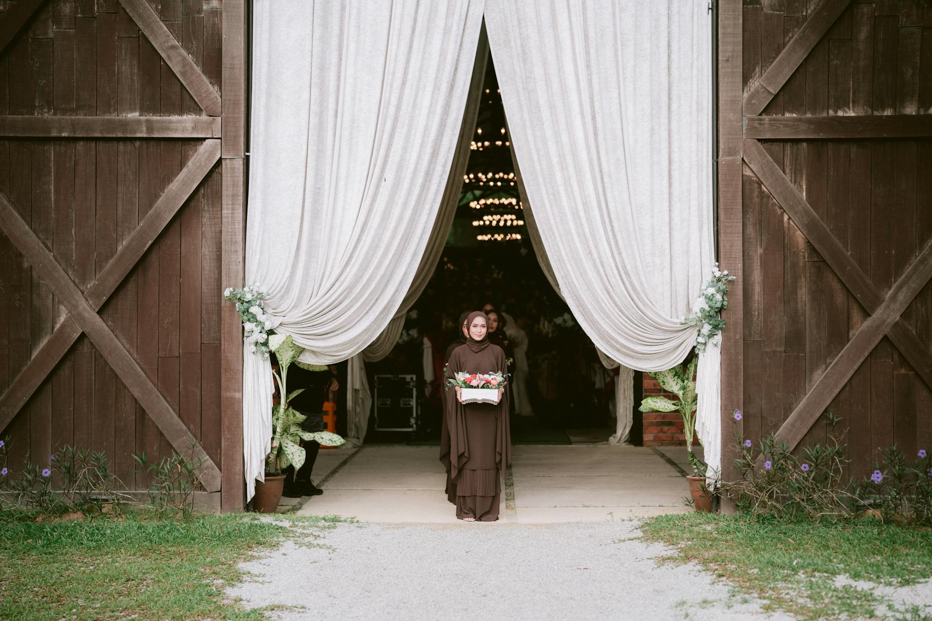 Panna młoda w brązowej sukni przed rustykalnym miejscem ślubu w plenerze