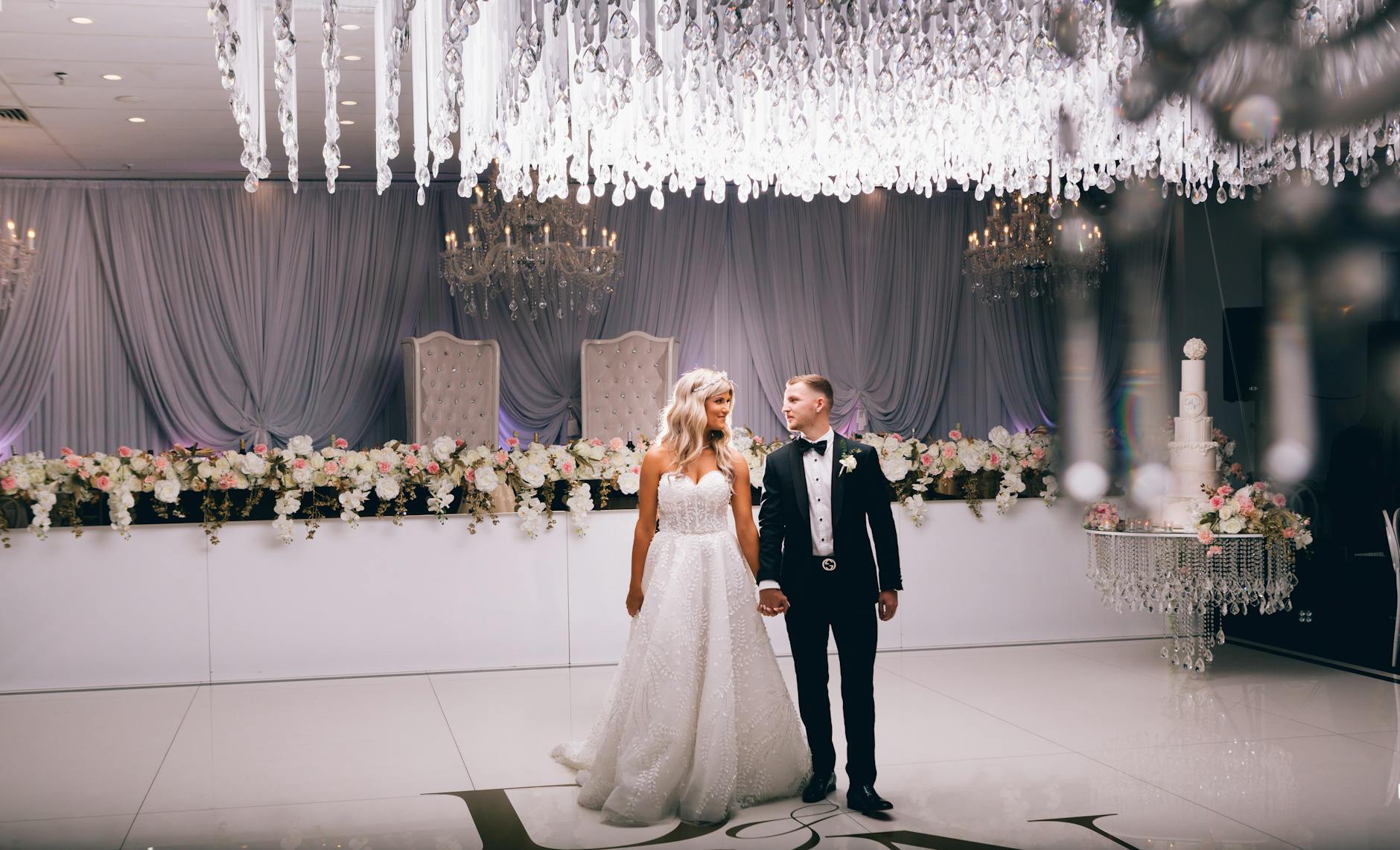 Para młoda na eleganckim weselu w sali z żyrandolami i kwiatami