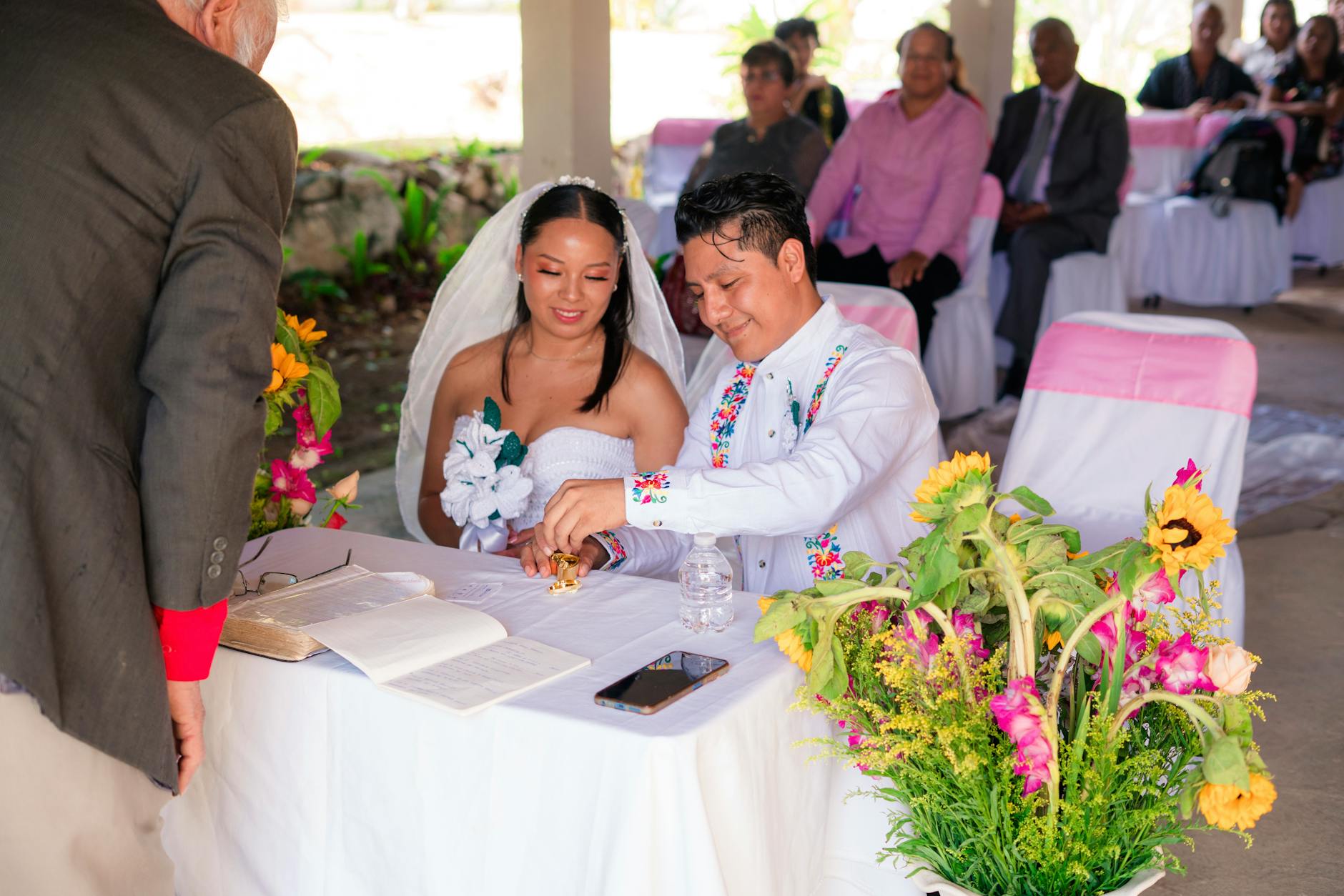 Ślub konkordatowy: jakie dokumenty i kiedy złożyć? Para młoda podpisuje dokumenty ślubne podczas plenerowej ceremonii