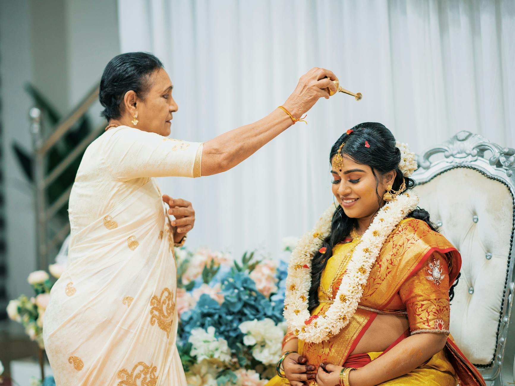 Starsza kobieta błogosławi młodą pannę młodą w indyjskim stroju