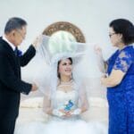 Jak wyjaśnić rodzinie, że robicie ślub bez tradycyjnych oczepin i dlaczego to okej Panna młoda z rodziną podczas radosnego świętowania w sali z kwiatami