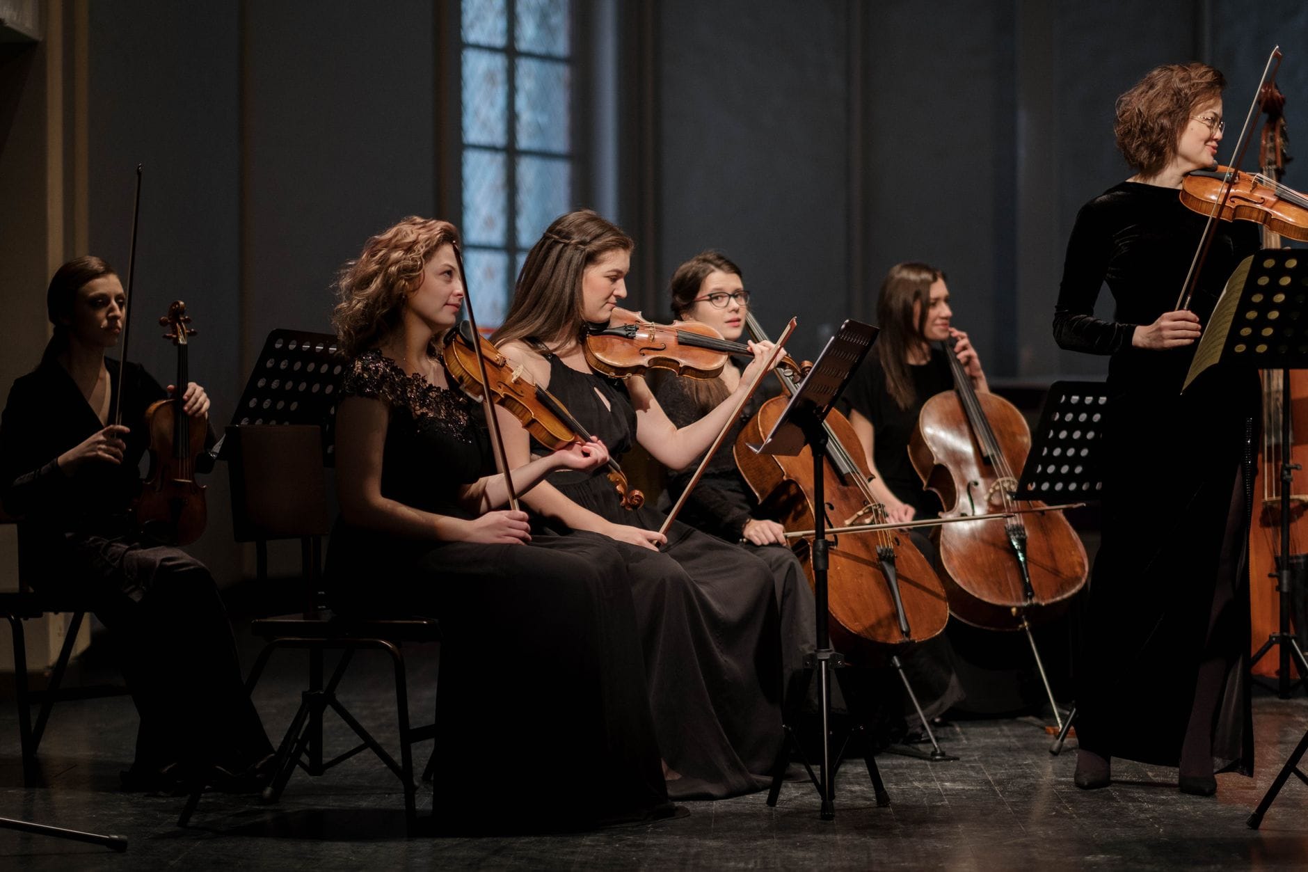 Grupa muzyczek gra klasyczną muzykę na skrzypcach w sali koncertowej